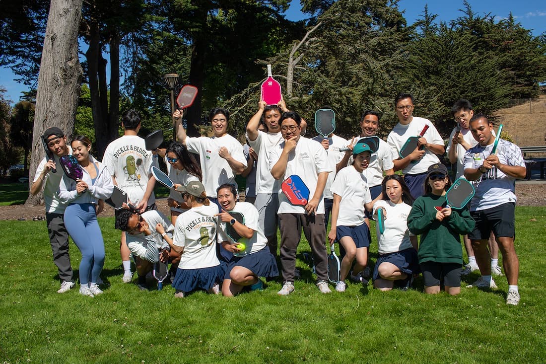 The whole club posing with paddles on the park lawn