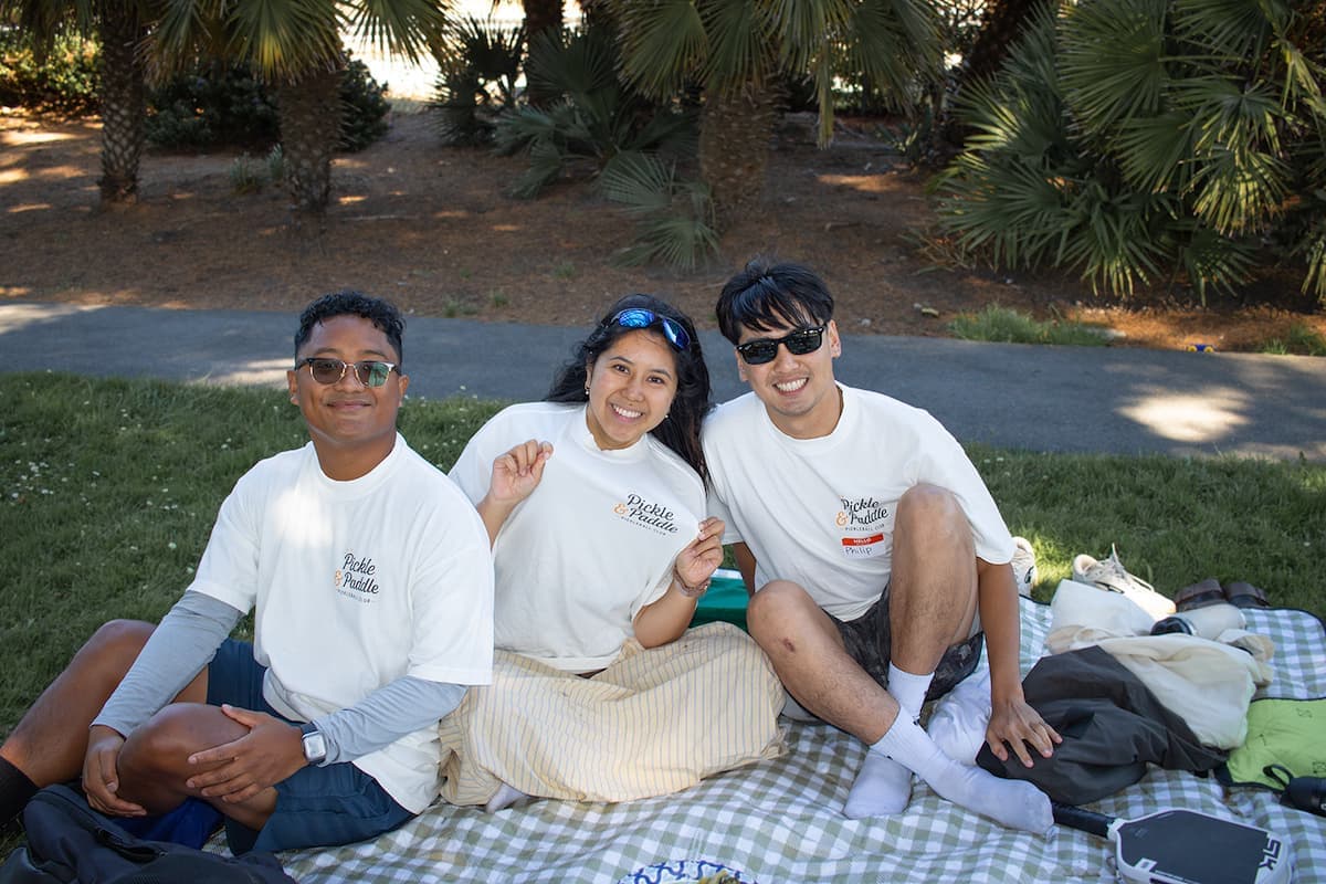 Three members relaxing on a picnic blanket after games