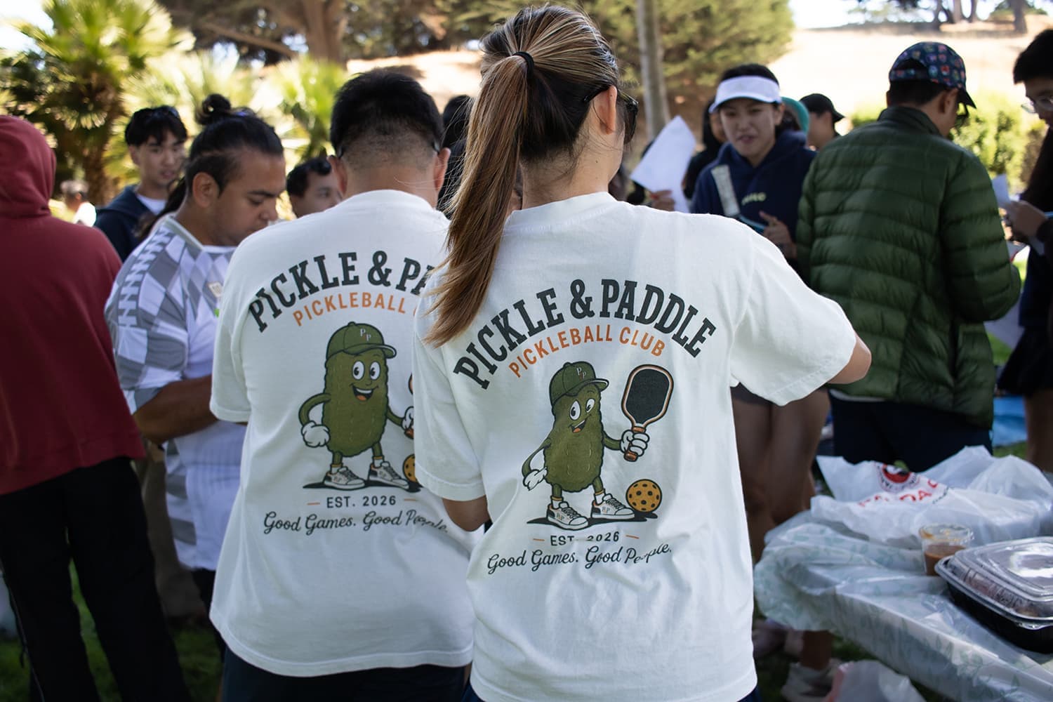 Members in club tees gathered at a park picnic